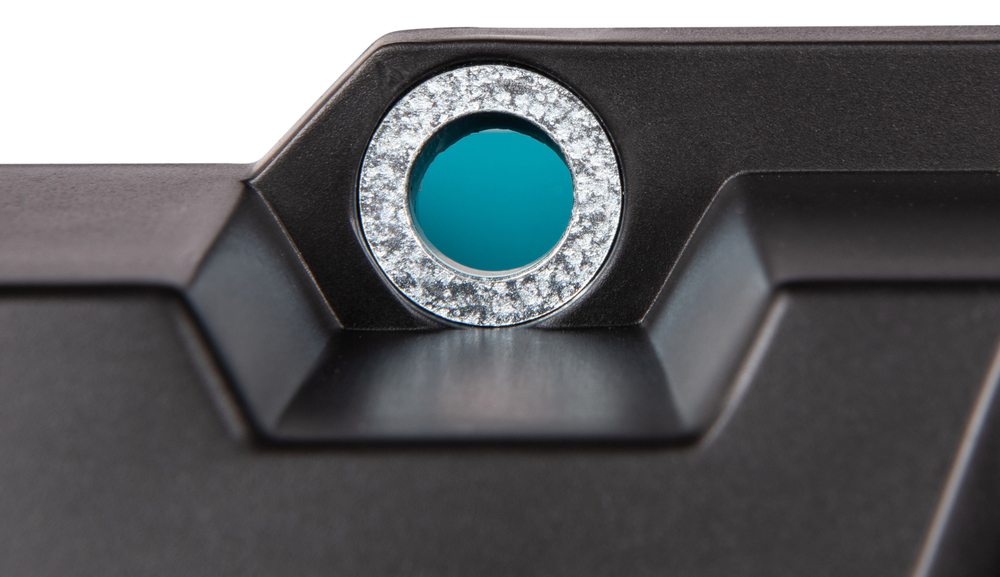 Detailaufnahme eines metallischen Bauteils mit blauem Glaseinsatz Nahaufnahme eines schwarzen Metallstücks mit kreisförmigem, blauem Glaselement in der Mitte