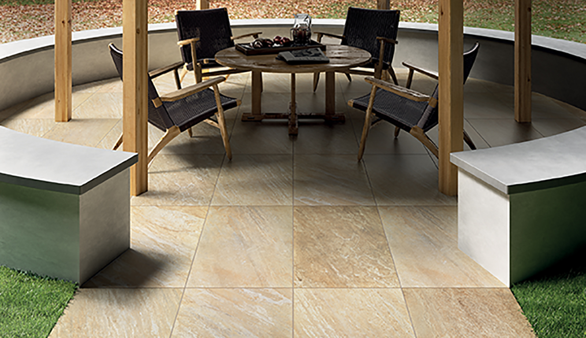 Überdachter Terrassenbereich mit Holztisch und Stühlen auf großen Natursteinfliesen