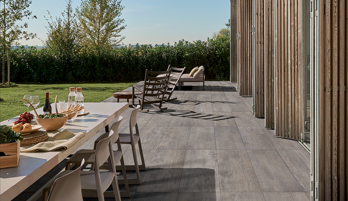 Moderne Terrasse mit Gartenmöbeln und Esstisch im Freien Terrasse mit Tisch gedeckt für ein Essen im Freien, umgeben von Liegestühlen und grüner Hecke