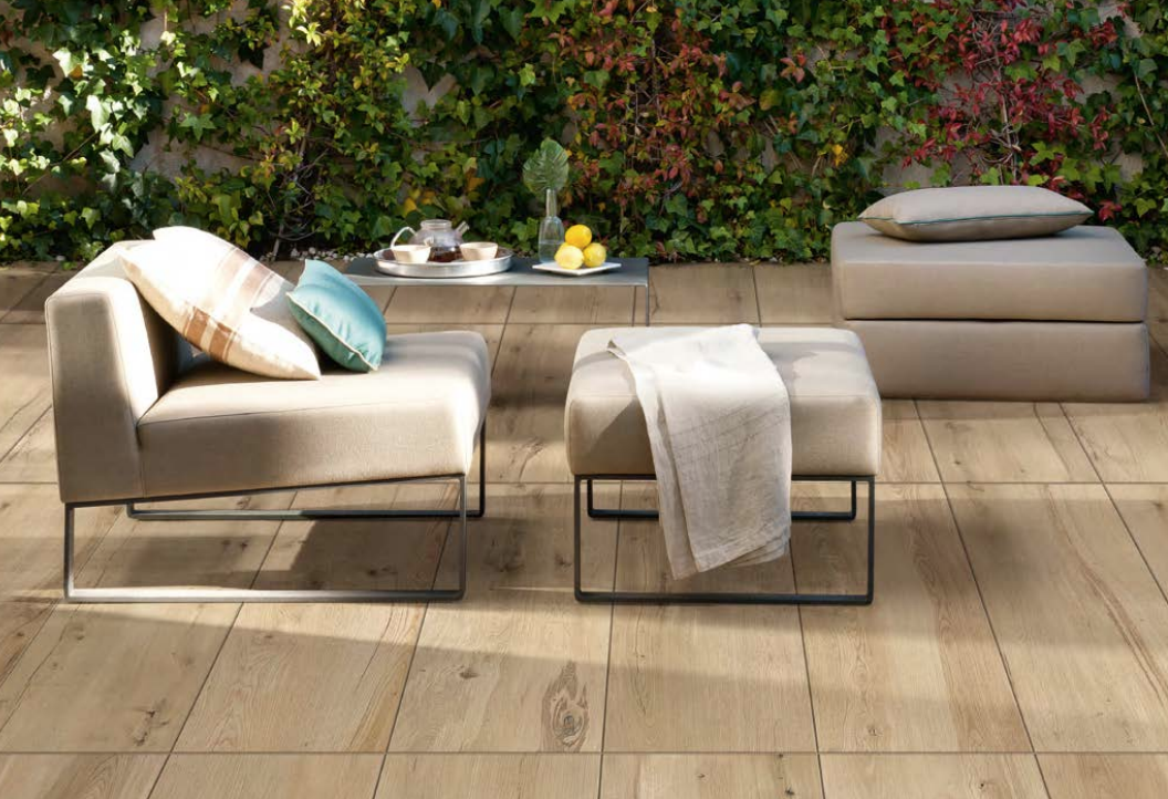 Ein stilvolles Gartenlounge-Set vor einer begrünten Wand mit bequemen Polstermöbeln und einem Couchtisch, auf dem Tee und Zitronen stehen.